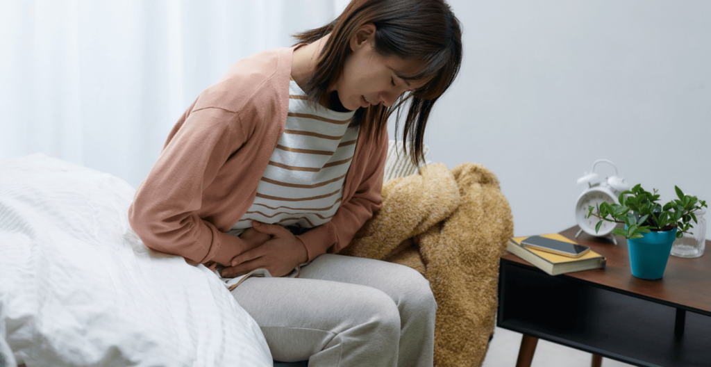 Mujer retorciendose por el dolor estomacal